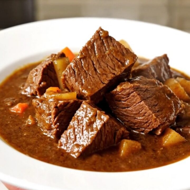 Bœuf bourguignon mijoté dans une mijoteuse noire sur un plan de travail en quartz blanc.