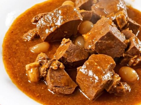 Mijoté de veau façon basquaise servi dans une assiette blanche avec des poivrons colorés.