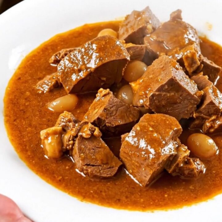 Mijoté de veau façon basquaise servi dans une assiette blanche avec des poivrons colorés.