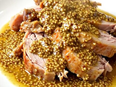 A close-up of tender turkey cubes in a creamy mustard sauce inside a black slow cooker.