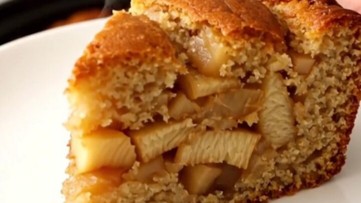 Gâteau aux pommes doré et fondant, servi dans une assiette blanche avec des reflets de lumière naturelle.