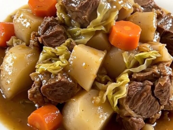 A rustic slow cooker filled with chunks of pork belly, beef, carrots, turnips, and cabbage in a savory broth.