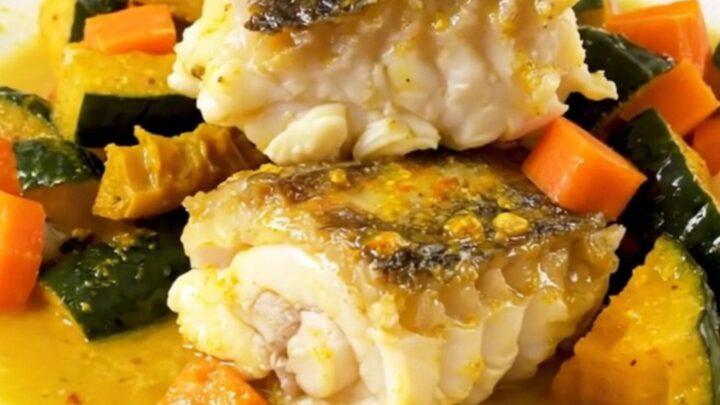 A top-down view into a slow cooker filled with monkfish, autumn vegetables, and a creamy saffron sauce.
