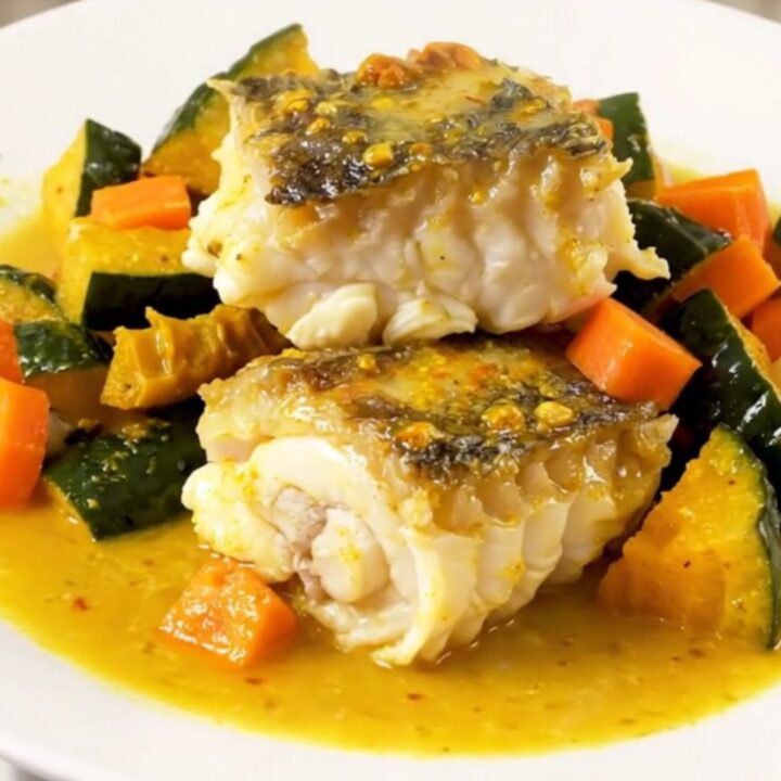 A top-down view into a slow cooker filled with monkfish, autumn vegetables, and a creamy saffron sauce.