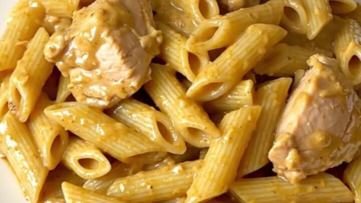 A close-up of creamy mustard chicken penne served on a white plate.
