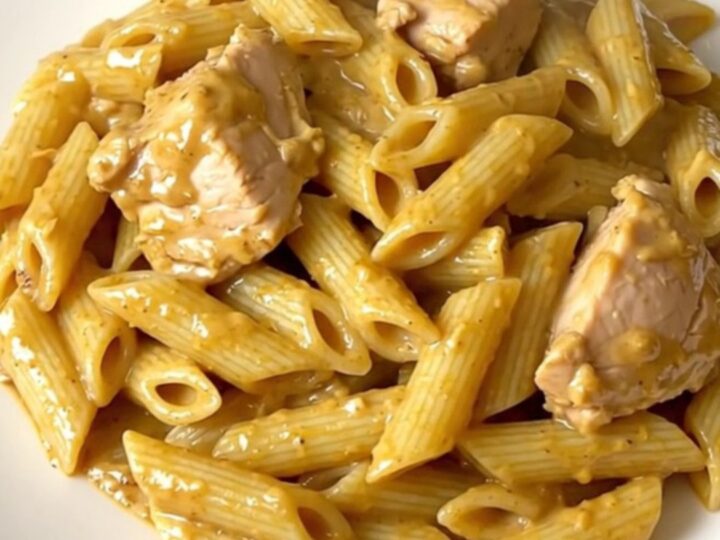 A close-up of creamy mustard chicken penne served on a white plate.