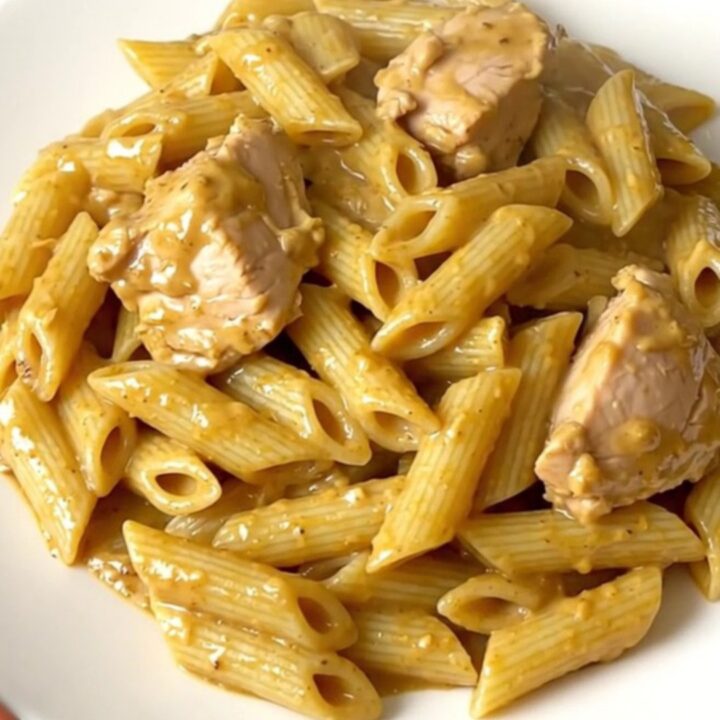 A close-up of creamy mustard chicken penne served on a white plate.