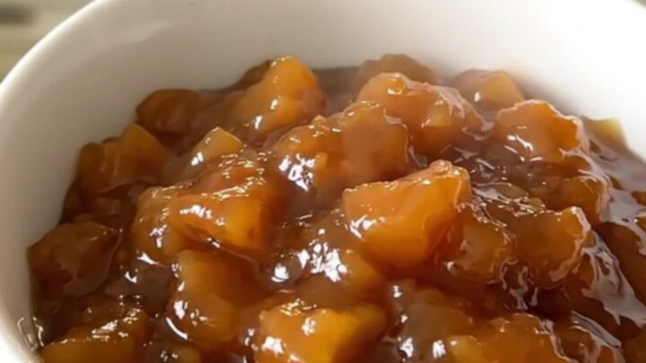 Glossy, warm compote of sliced quince, apple, and pear served in a simple white ceramic bowl.