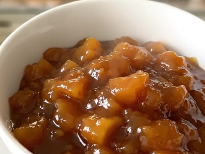 Glossy, warm compote of sliced quince, apple, and pear served in a simple white ceramic bowl.