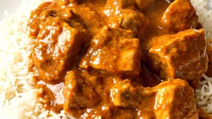 A top-down view of creamy slow cooker butter chicken served over white rice on a clean white plate.
