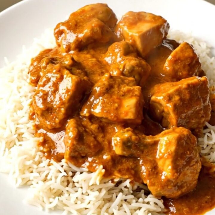 A top-down view of creamy slow cooker butter chicken served over white rice on a clean white plate.