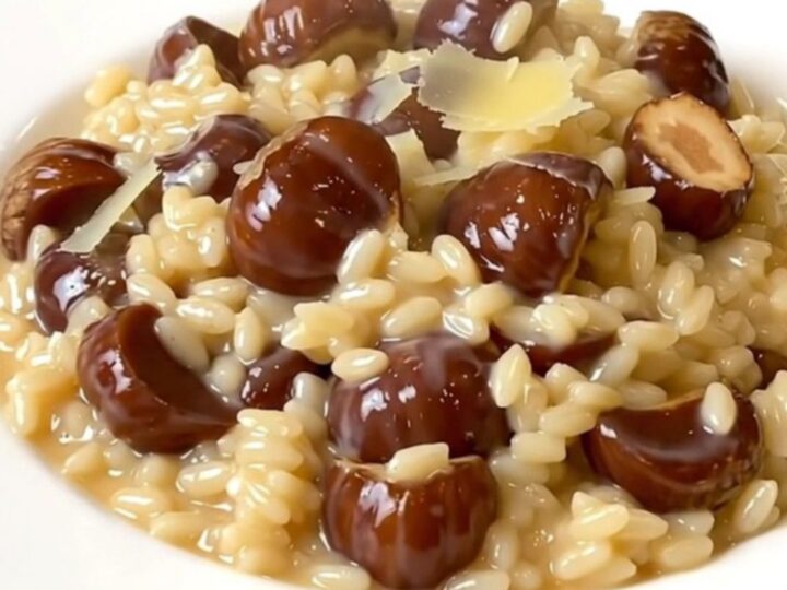 A top-down view of a black slow cooker filled with creamy chestnut and parmesan risotto on a white speckled countertop.
