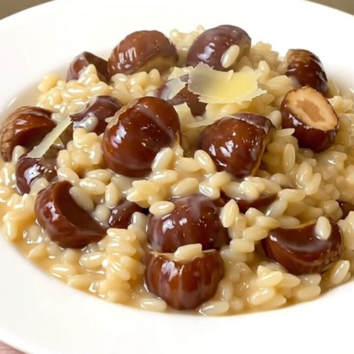 A top-down view of a black slow cooker filled with creamy chestnut and parmesan risotto on a white speckled countertop.