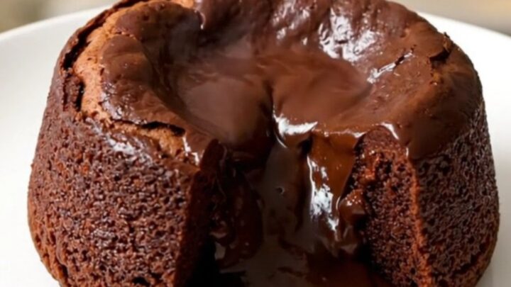 A warm, gooey praline chocolate molten cake served on a white plate with a spoon.