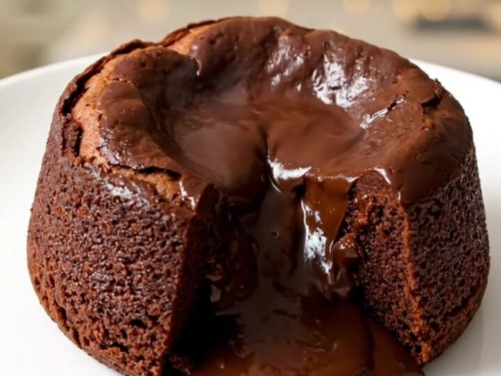 A warm, gooey praline chocolate molten cake served on a white plate with a spoon.