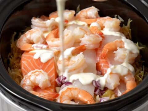 A steaming, elegant seafood and sauerkraut dish served in a white bowl with a drizzle of cream.