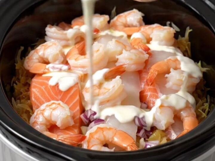 A steaming, elegant seafood and sauerkraut dish served in a white bowl with a drizzle of cream.