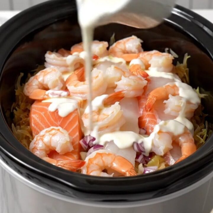 A steaming, elegant seafood and sauerkraut dish served in a white bowl with a drizzle of cream.