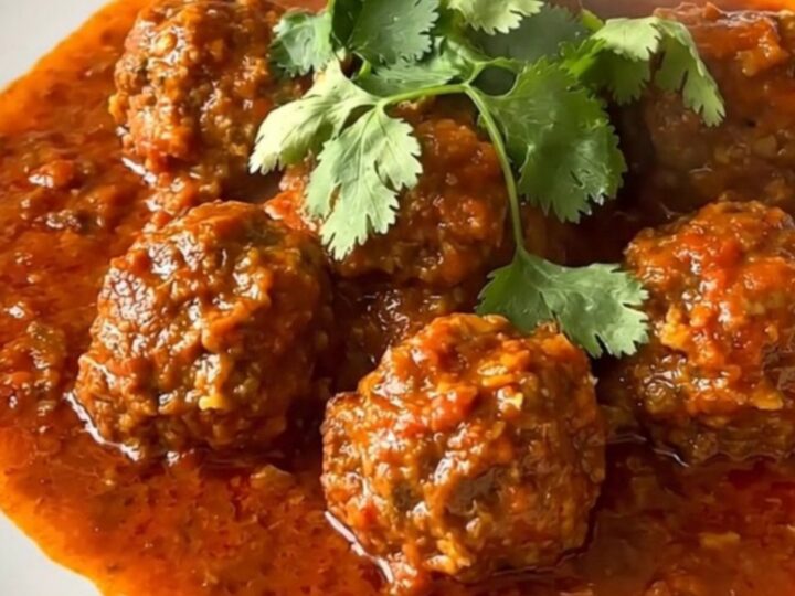 A steaming, flavorful beef kefta tagine served in a white bowl with a rich tomato sauce.