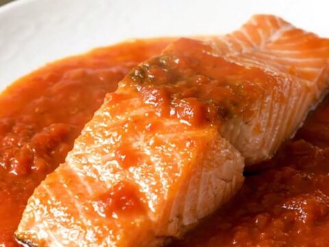 A close-up view of cooked salmon fillets topped with tomato coulis and onions in a slow cooker.