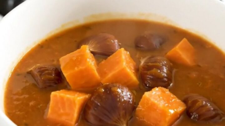 A rustic slow cooker sweet potato and chestnut stew served in a white bowl with fresh herbs.