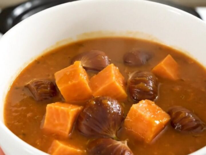 A rustic slow cooker sweet potato and chestnut stew served in a white bowl with fresh herbs.