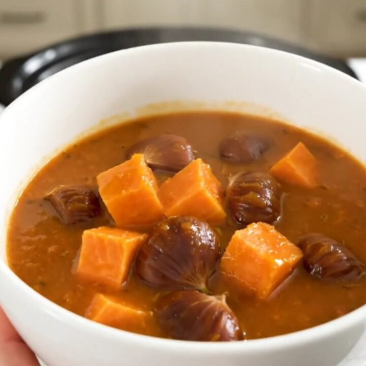A rustic slow cooker sweet potato and chestnut stew served in a white bowl with fresh herbs.