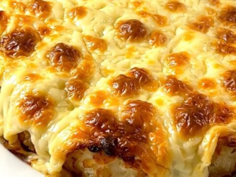 A steaming, creamy Munster tartiflette served on a white plate with melted cheese and visible cumin seeds.
