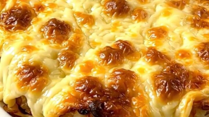 A steaming, creamy Munster tartiflette served on a white plate with melted cheese and visible cumin seeds.