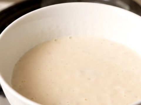 A warm bowl of creamy homemade eggnog garnished with a light dusting of freshly grated nutmeg.