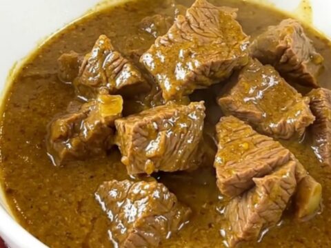 A bowl of slow-cooked coconut mild beef curry with carrots and yellow bell peppers.
