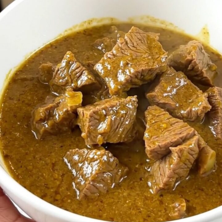 A bowl of slow-cooked coconut mild beef curry with carrots and yellow bell peppers.