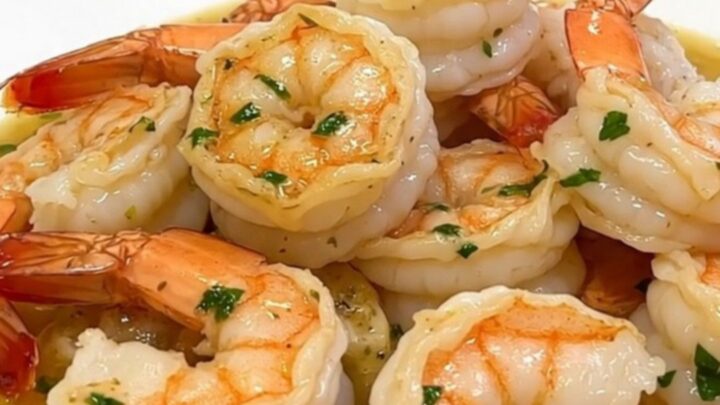 A top-down view of raw shrimp, parsley, garlic, and cream inside a black slow cooker insert.