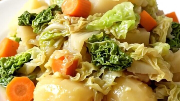 A top-down view of a black slow cooker filled with layers of shredded Savoy cabbage, potato wedges, and sliced carrots.