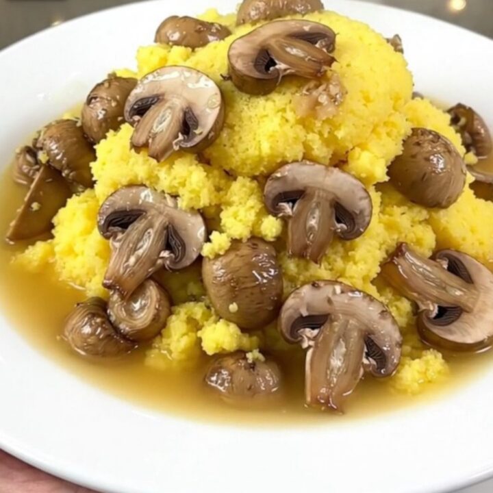 A close-up of a creamy parmesan polenta dish with mushrooms served in a white bowl with a garnish.