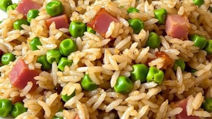 A top-down view of a black slow cooker filled with white rice, peas, and ham, ready for cooking.