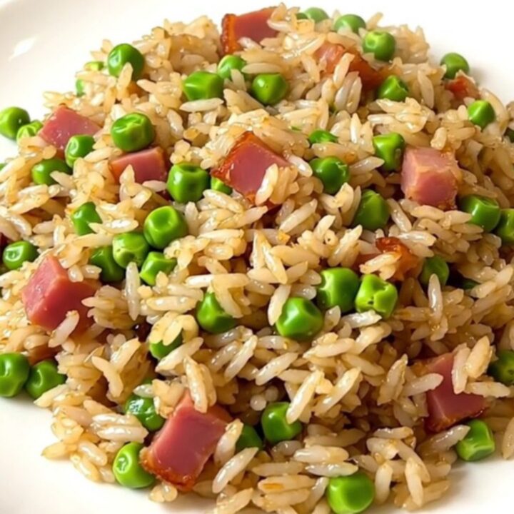 A top-down view of a black slow cooker filled with white rice, peas, and ham, ready for cooking.