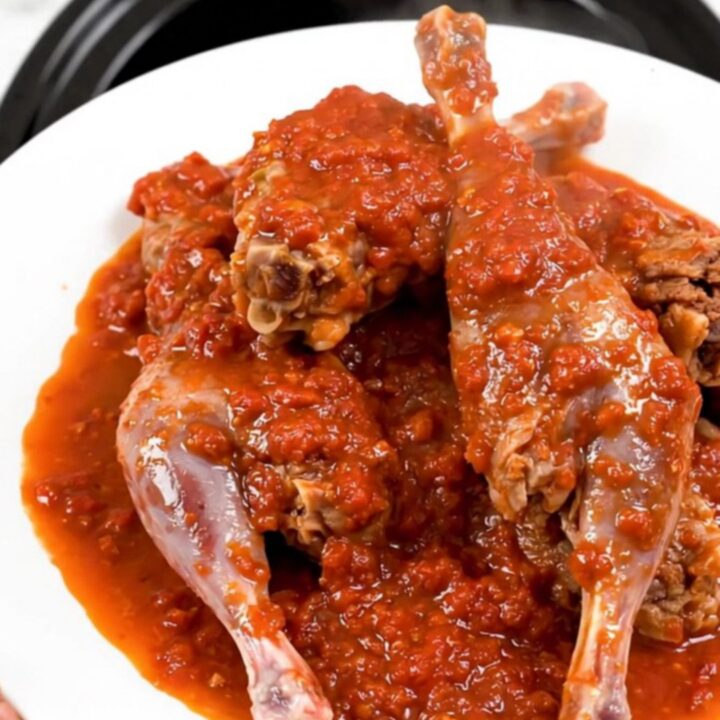 A rustic slow cooker filled with Provencal rabbit in a rich tomato sauce with rosemary sprigs and olives.
