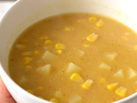A bowl of golden, creamy sweet corn and potato velouté, perfectly smooth and steaming, set on a bright kitchen counter.