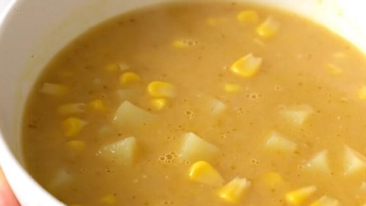A bowl of golden, creamy sweet corn and potato velouté, perfectly smooth and steaming, set on a bright kitchen counter.