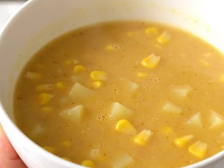 A bowl of golden, creamy sweet corn and potato velouté, perfectly smooth and steaming, set on a bright kitchen counter.