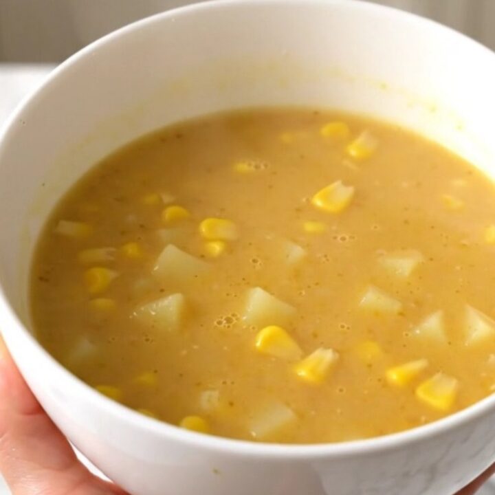 A bowl of golden, creamy sweet corn and potato velouté, perfectly smooth and steaming, set on a bright kitchen counter.