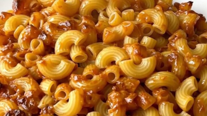 A close-up of creamy mac and cheese in a slow cooker with visible melted cheese and herbs.