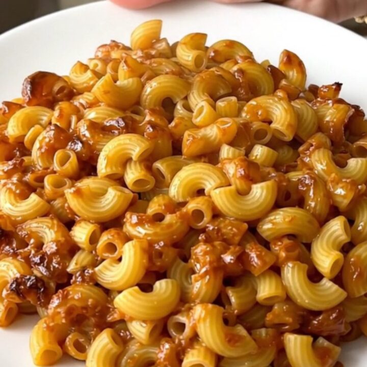 A close-up of creamy mac and cheese in a slow cooker with visible melted cheese and herbs.