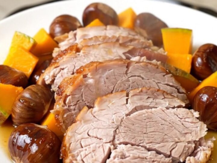 A slow cooker filled with a pork roast, chunks of red kuri squash, and whole chestnuts.
