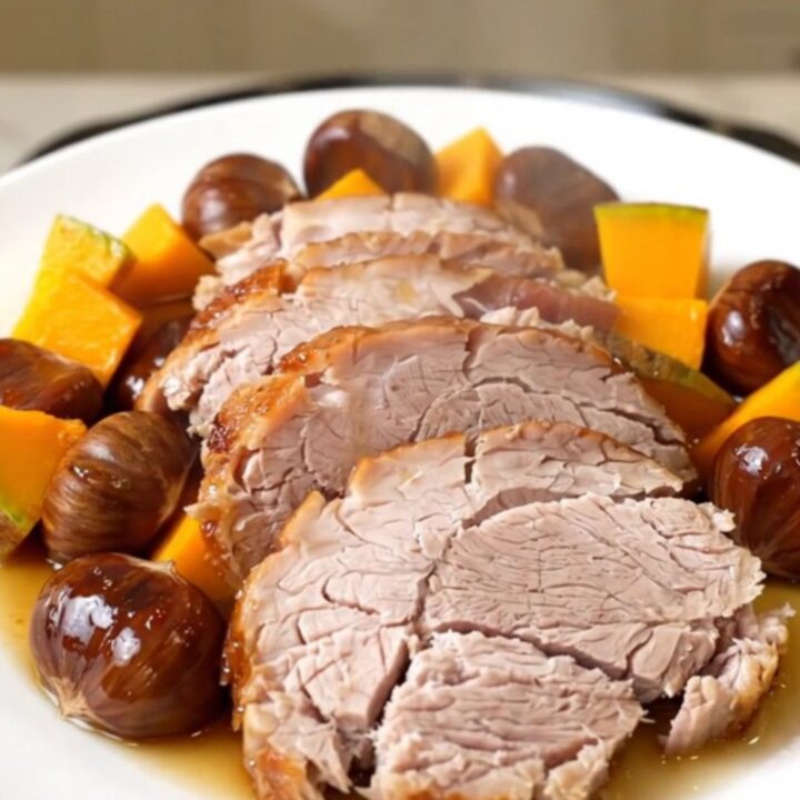 A slow cooker filled with a pork roast, chunks of red kuri squash, and whole chestnuts.