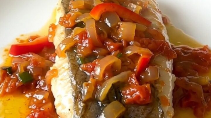 A plate of tender white hake fillets topped with a colorful piperade sauce of red peppers and onions.