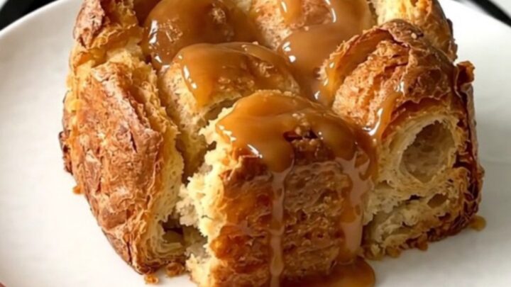 A warm, golden bread pudding in a slow cooker, topped with tender apple slices and a drizzle of salted butter caramel.