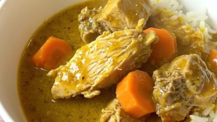 A steaming, glossy bowl of turkey curry with carrots served over white rice.