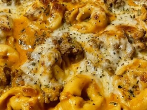 A bubbly cast iron skillet filled with creamy beef and cheese tortellini, topped with melted mozzarella.